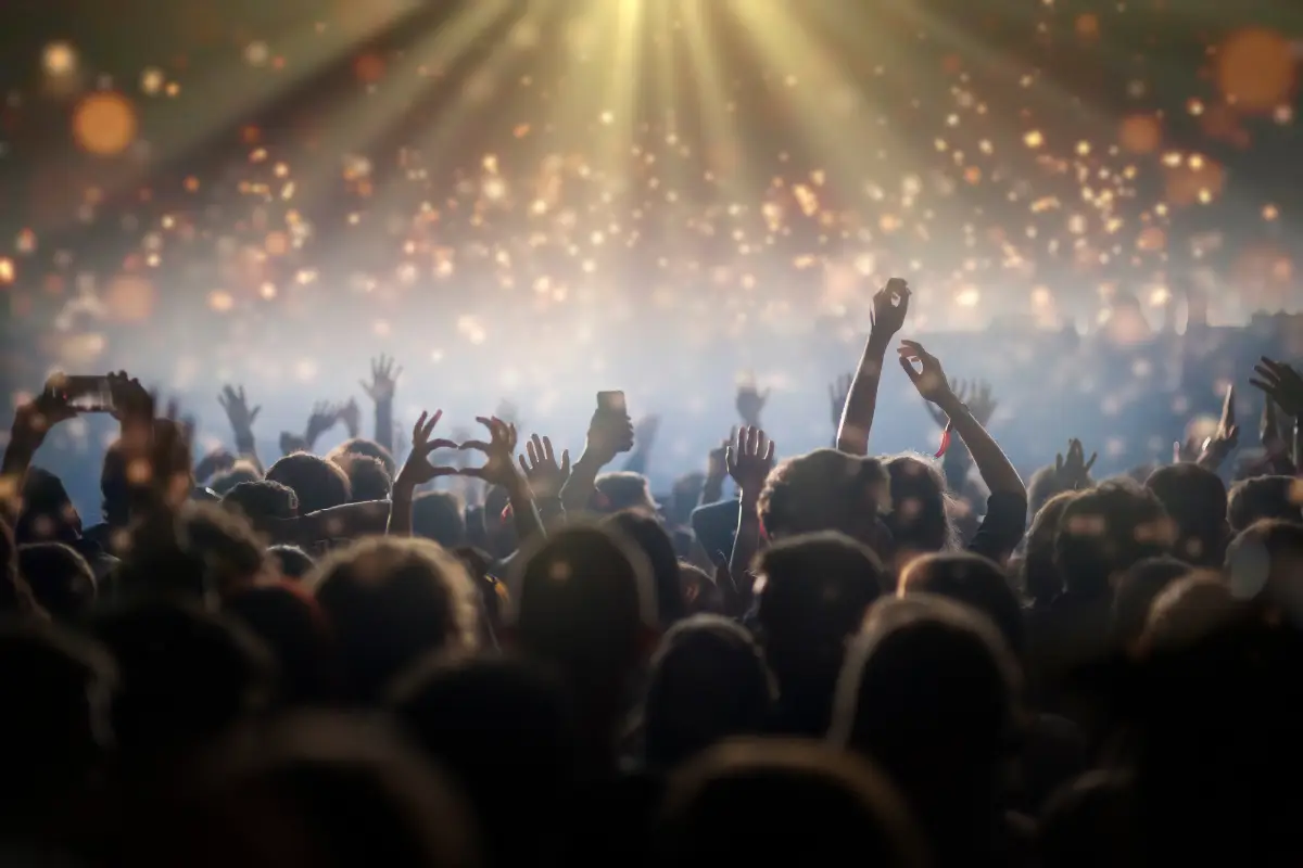 Concert crowd with hands raised under warm stage lights at a live music show near Playa del Carmen