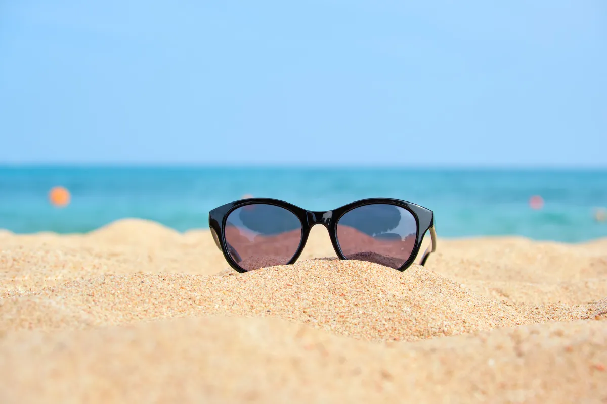 Sunglasses on warm sand on a clear, sunny beach day, the best time to visit Playa del Carmen